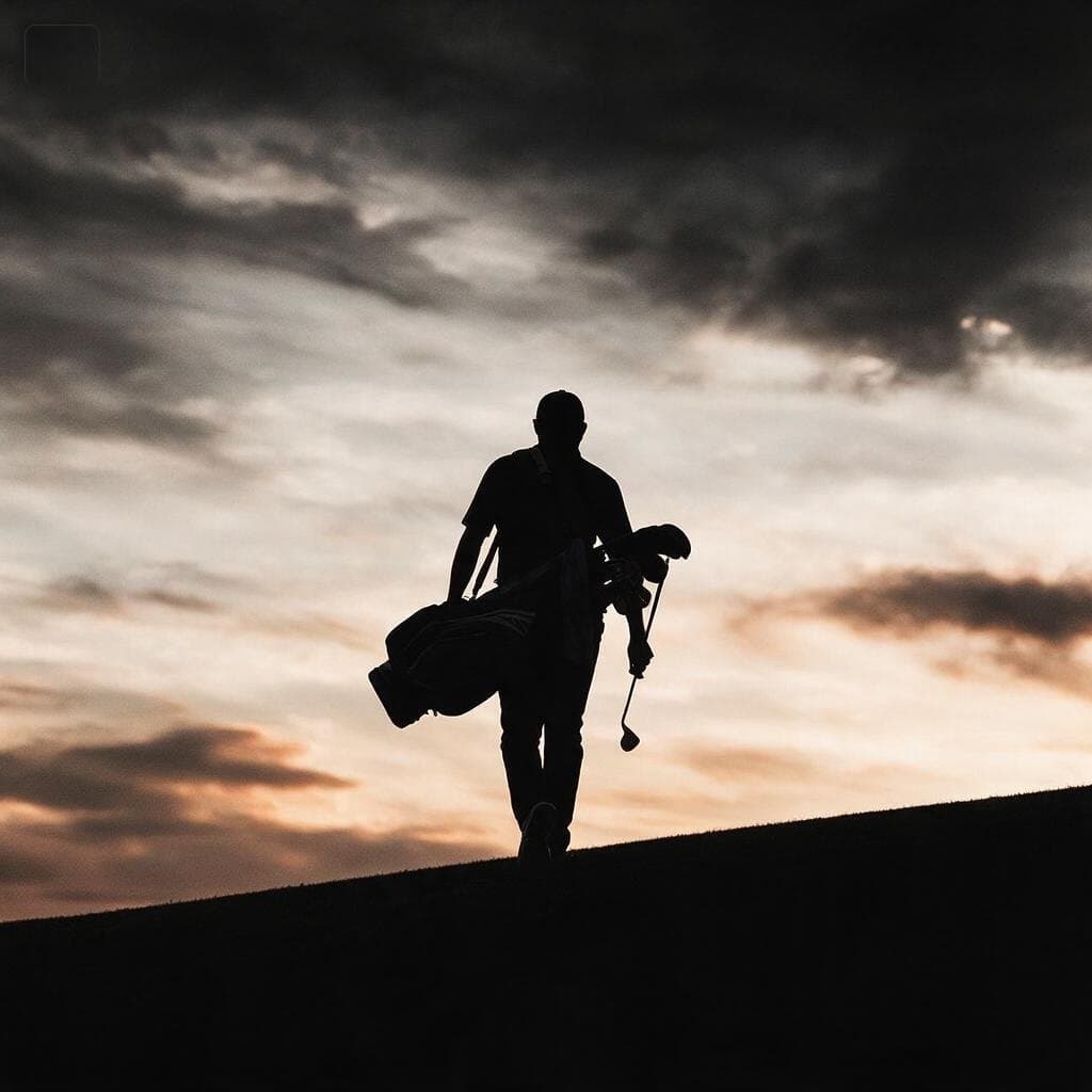 La silueta de un jugador con la bolsa al hombro caminando hacia el atardecer